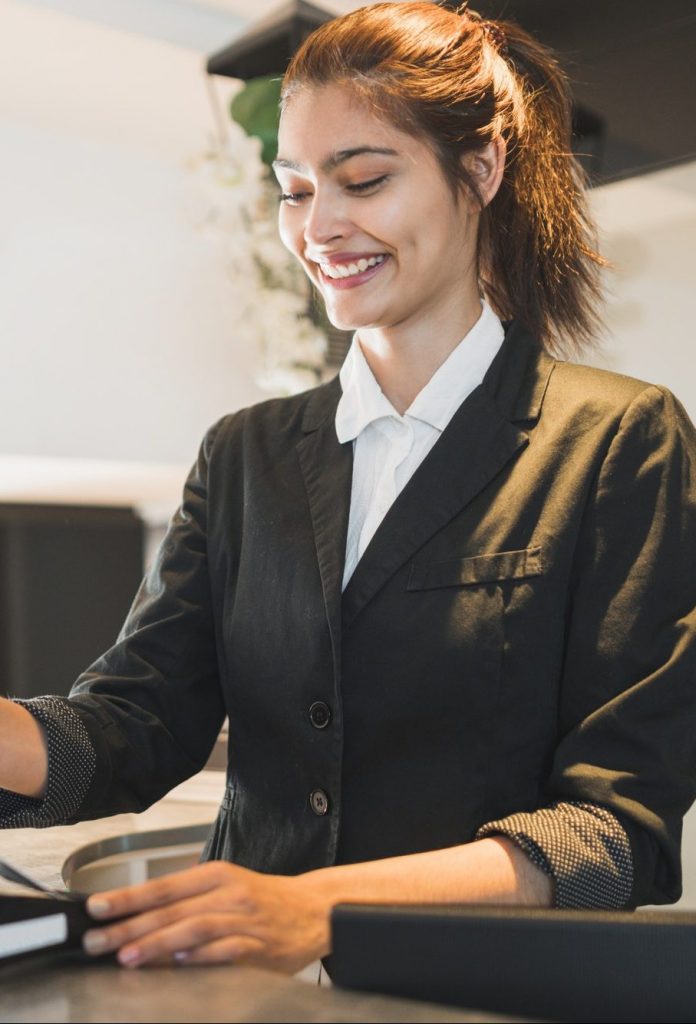 Receptionist passing card and charging guest stay at reception.